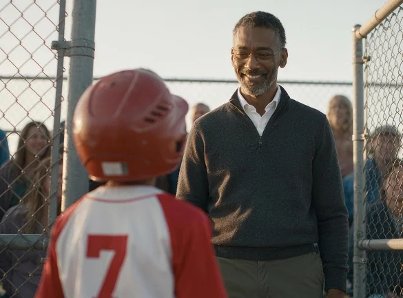 Father smiling at son at little league game